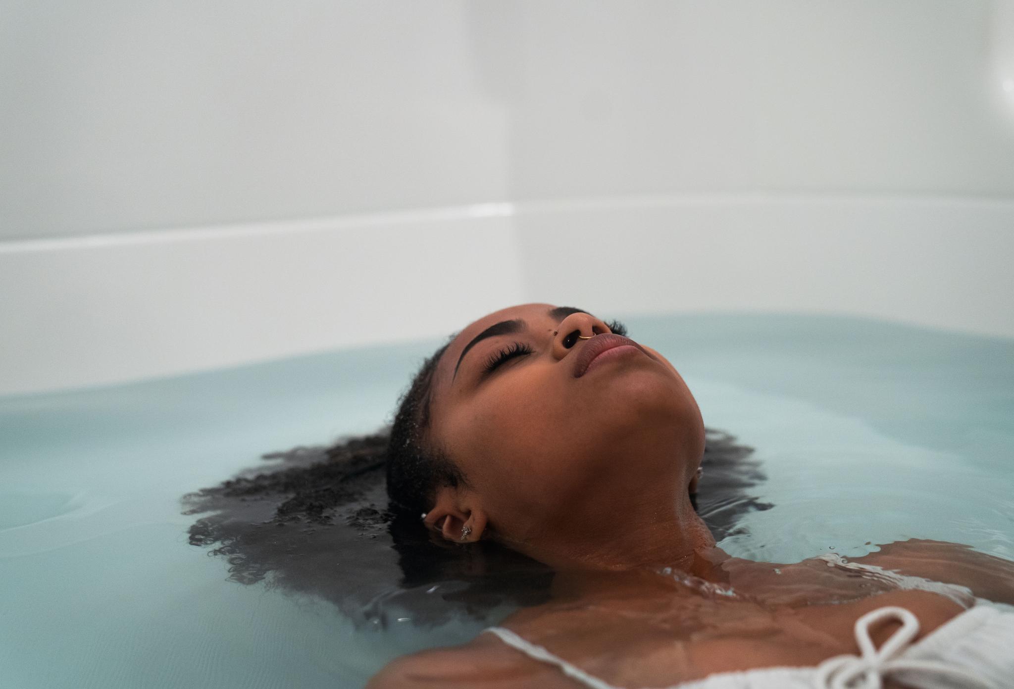 Woman floating peacefully during frequency therapy, promoting relaxation, stress relief, and inner calm with Floatation REST