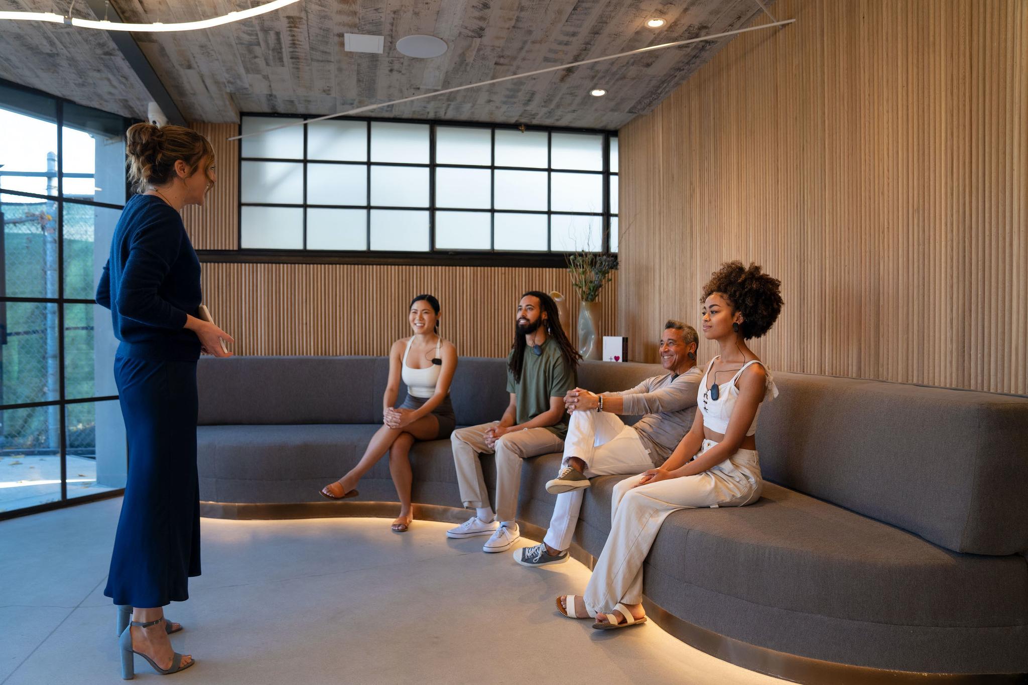Wellness guide engaging a diverse group of clients in a modern relaxation lounge at Quantum Clinic